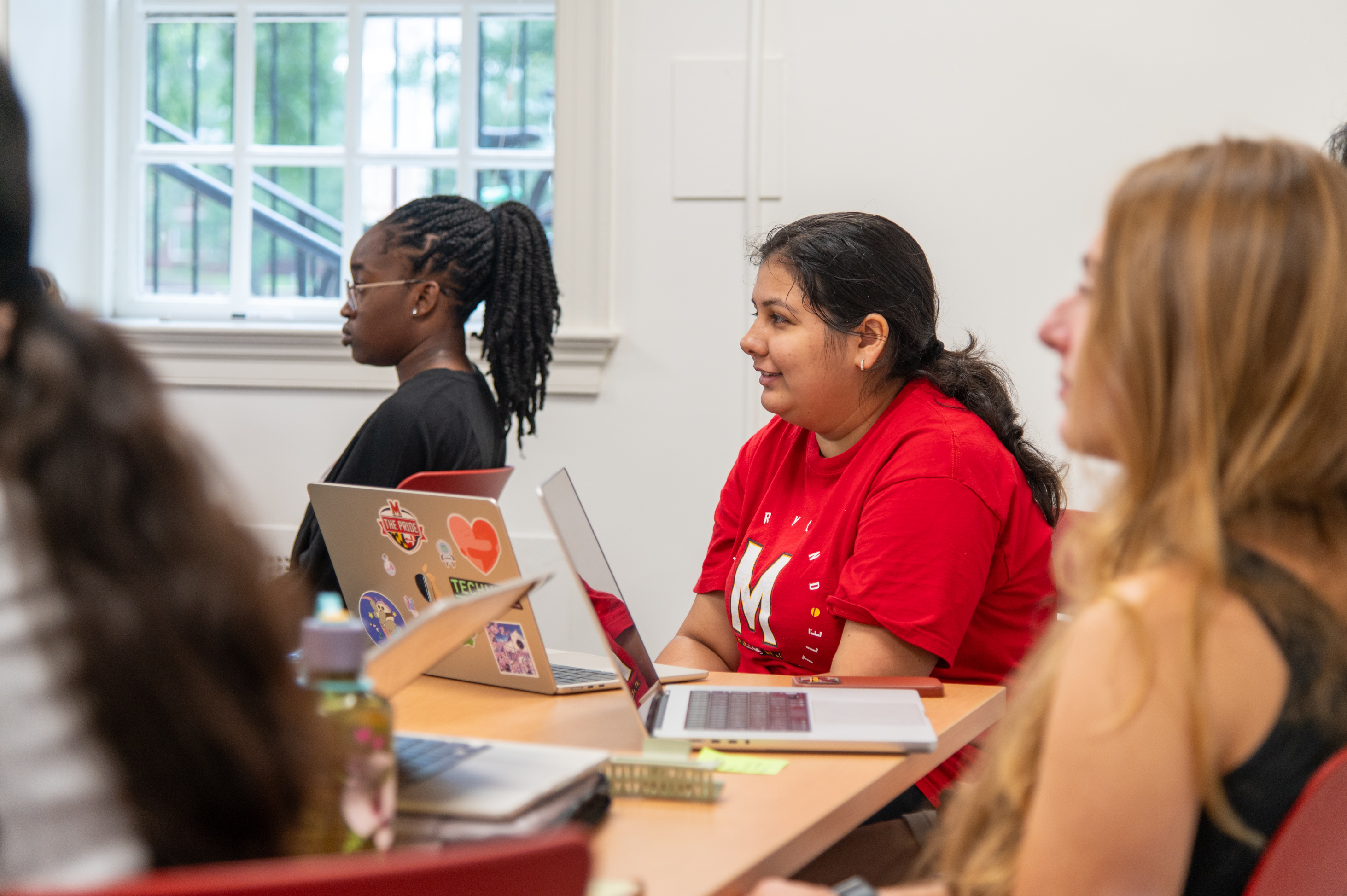 students with laptops face presenter