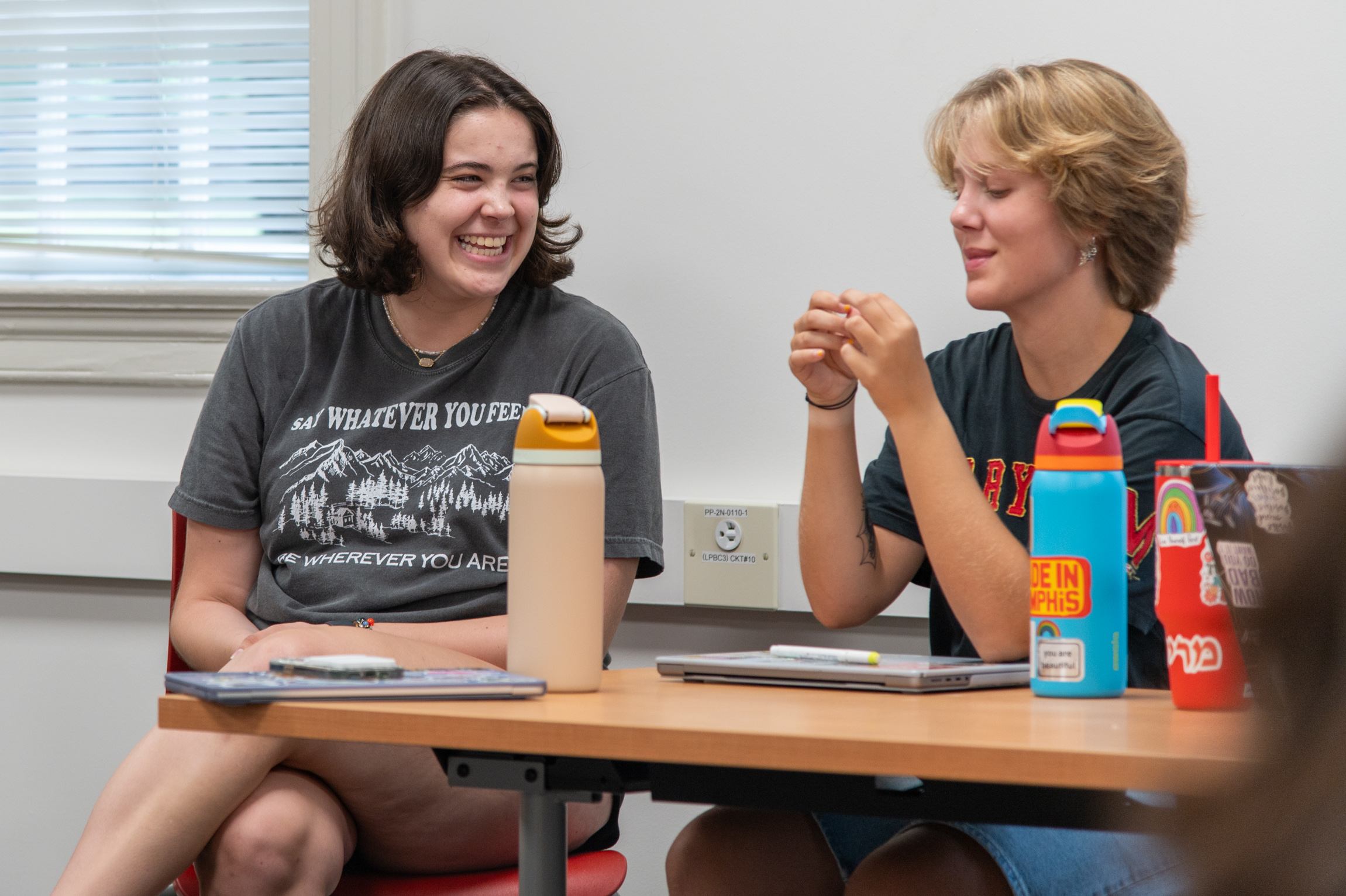 student smiling next to student looking at hands