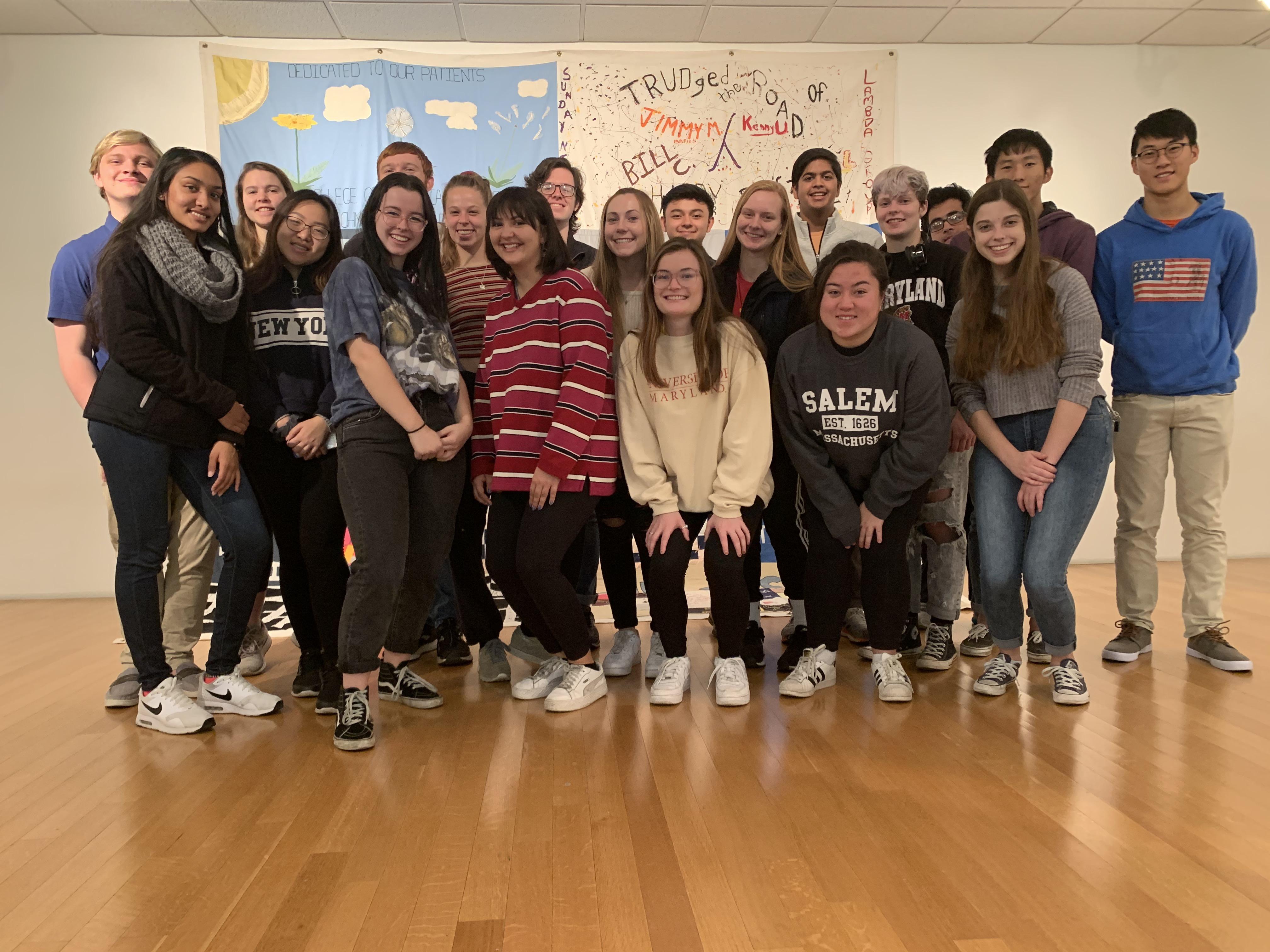 group of students pose in front of quilt