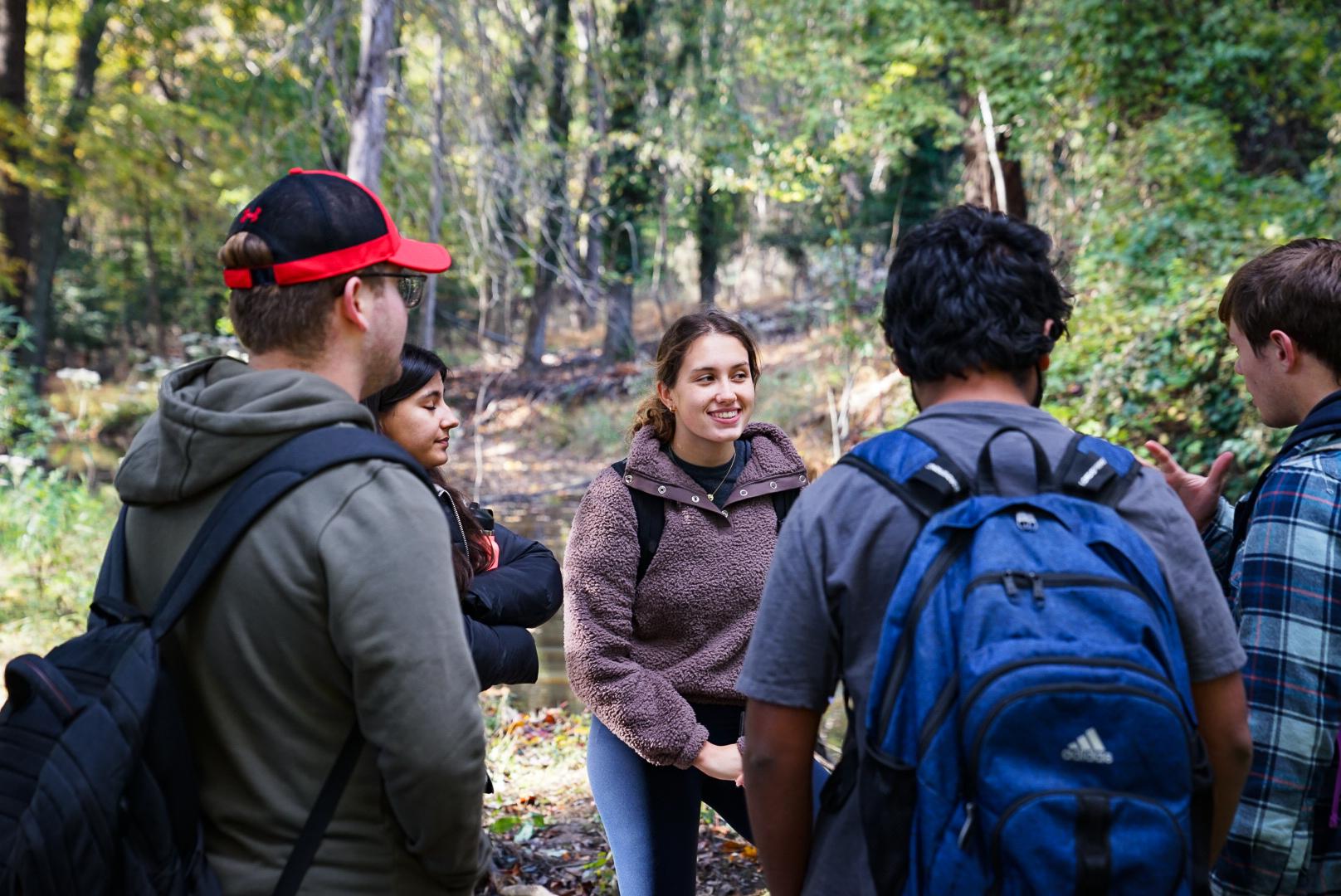 student talking in a wooded area