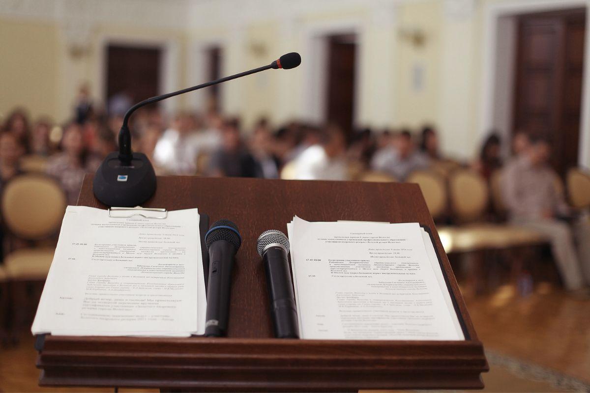 podium with two microphones and speeches